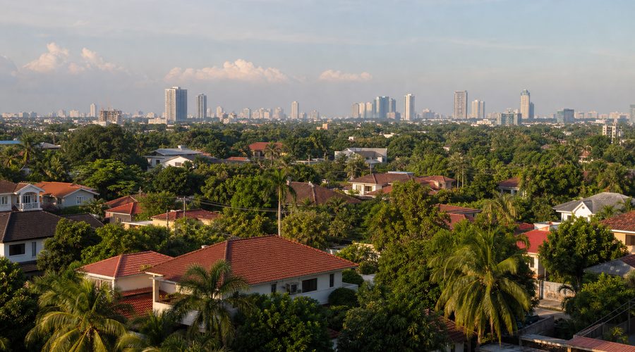 Leafy low-rise housing in southern Metro Manila with distant towers on the horizon