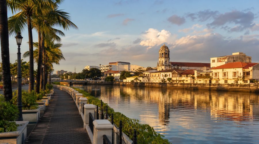 The riverside esplanade in Iloilo City at sunrise, with a church belfry across the water