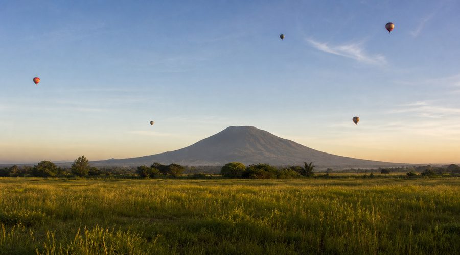 Hot-air balloons over the Central Luzon plain with a volcanic peak in the distance